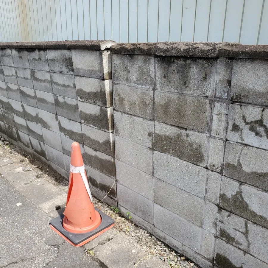 つなぎ目がずれ、ひびの入った道路沿いのブロック塀